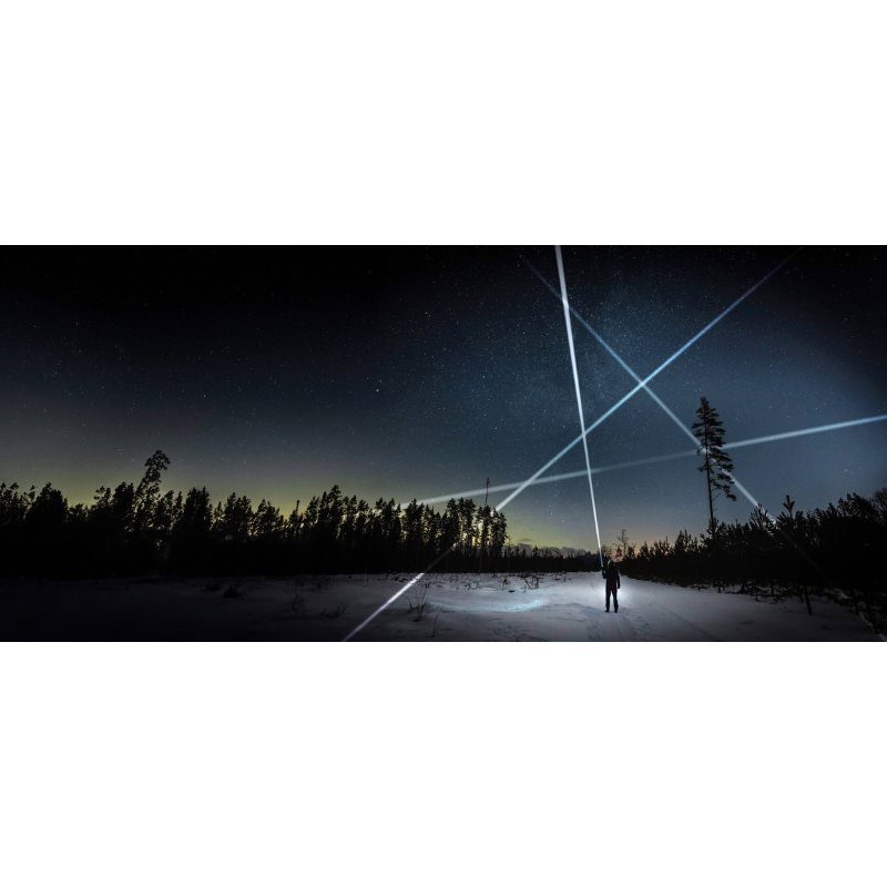 Eine Person steht auf einer verschneiten Lichtung unter einem klaren Sternenhimmel und richtet mehrere extrem starke Lichtstrahlen mit der Ledlenser P9R Signature in verschiedene Richtungen. Die Strahlen kreuzen sich eindrucksvoll über der winterlichen Landschaft. Die Szene zeigt die enorme Leuchtkraft und Reichweite der Taschenlampe, ideal für Outdoor-Abenteuer, Rettungseinsätze und professionelle Anwendungen.
